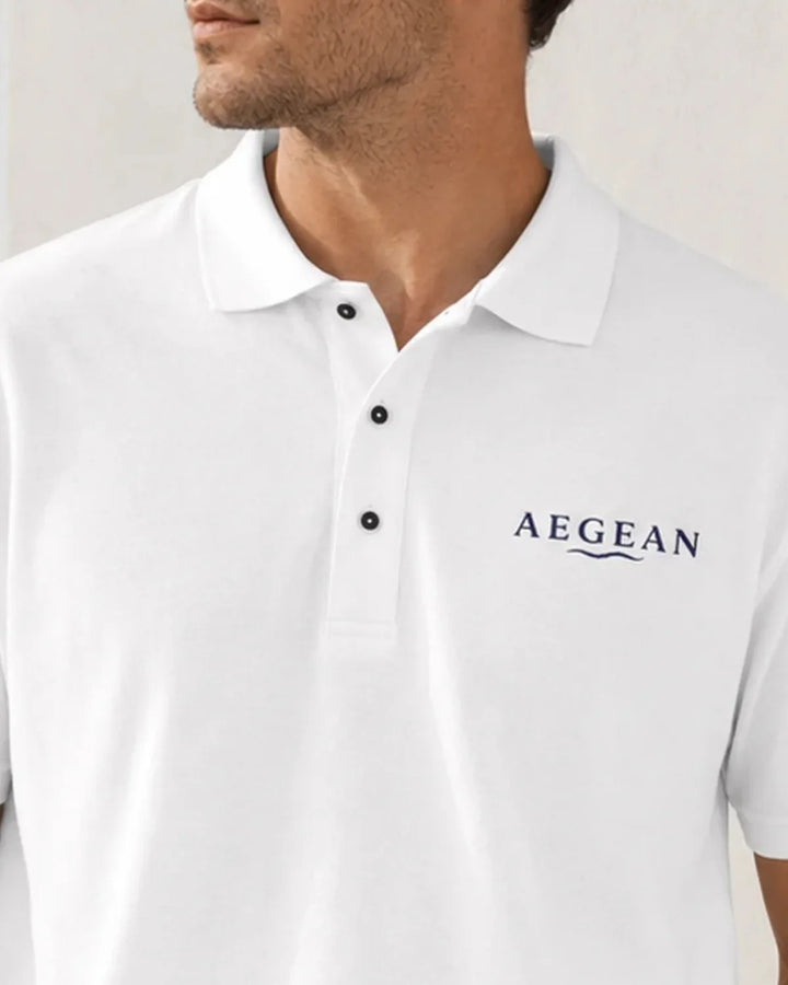 Model wearing the white AEGEAN embroidered polo in a Mediterranean setting