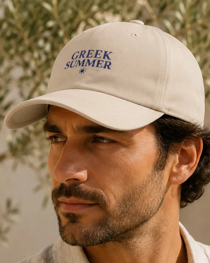 Model wearing the Stone Greek Summer embroidered cap in a Mediterranean setting
