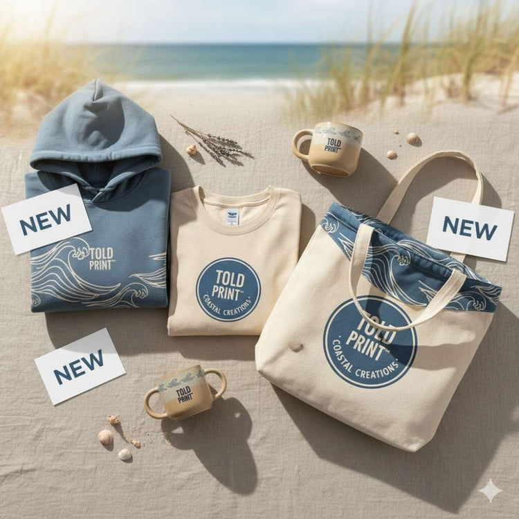 Lifestyle flat-lay of new apparel items — hoodie, t-shirt, tote bag with tags labeled “New.” Warm light, coastal backdrop, soft textures.