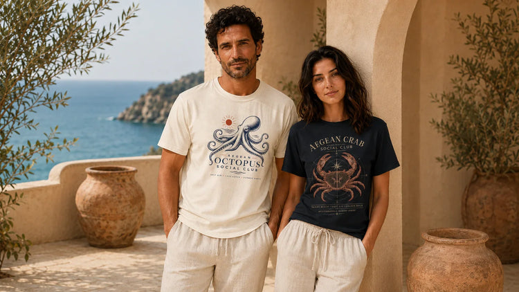 Image alt text: Aegean Social Club Mediterranean marine graphic T-shirts with octopus and crab artwork in a coastal summer setting