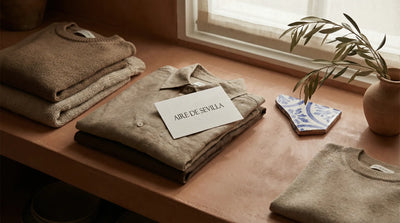 Spanish-inspired apparel flat lay with folded garments and ceramic details in warm window light