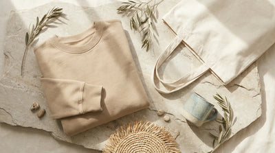 Minimal apparel and tote bag flat lay on light marble surface with natural Mediterranean elements