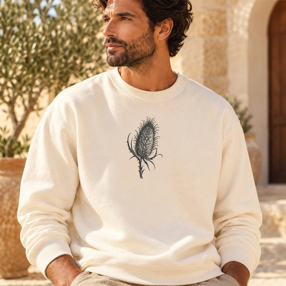 TP HERO: Cardó Ivory lightweight crewneck worn in a Mediterranean courtyard, original centered teasel artwork from the locked design