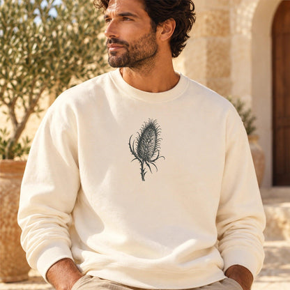 TP HERO: Cardó Ivory lightweight crewneck worn in a Mediterranean courtyard, original centered teasel artwork from the locked design