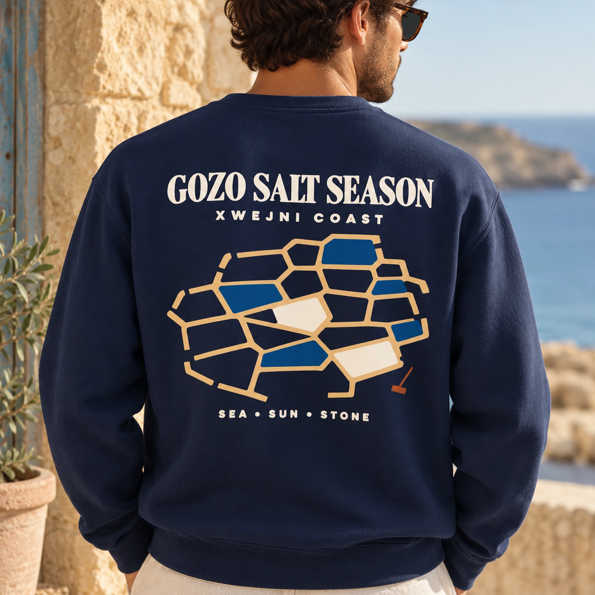Close-up model view of the Gozo Salt Season sweatshirt in True Navy, with the Xwejni salt-pan back design dominating the frame.