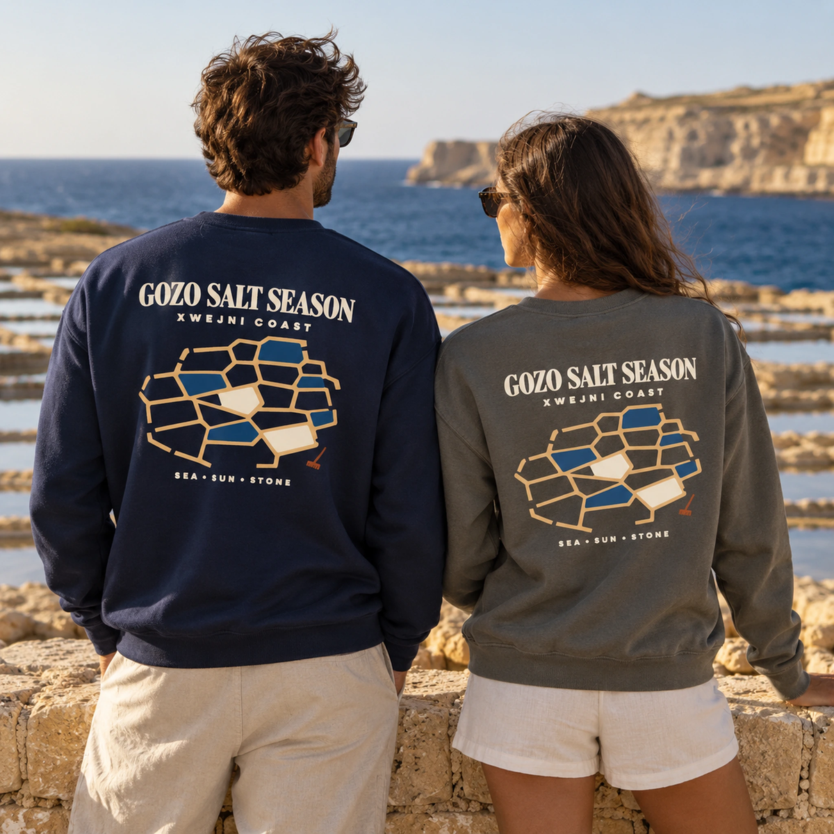 Lifestyle duo wearing Gozo Salt Season garment-dyed sweatshirts in True Navy and Pepper, inspired by the Xwejni salt pans of Gozo.