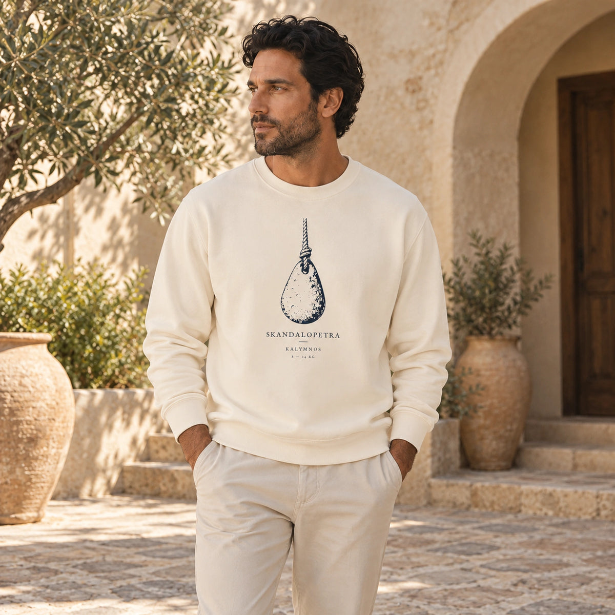 Male model wearing Skandalopetra Ivory lightweight crewneck in a Mediterranean courtyard, front view