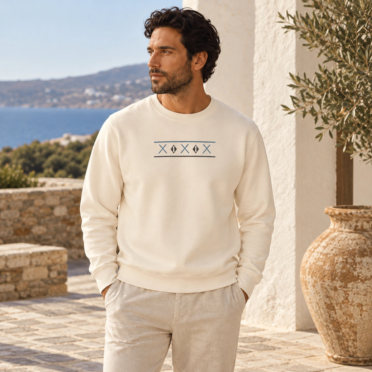 Male model wearing the Tinos Dovecote Geometry Ivory crewneck in a Mediterranean courtyard