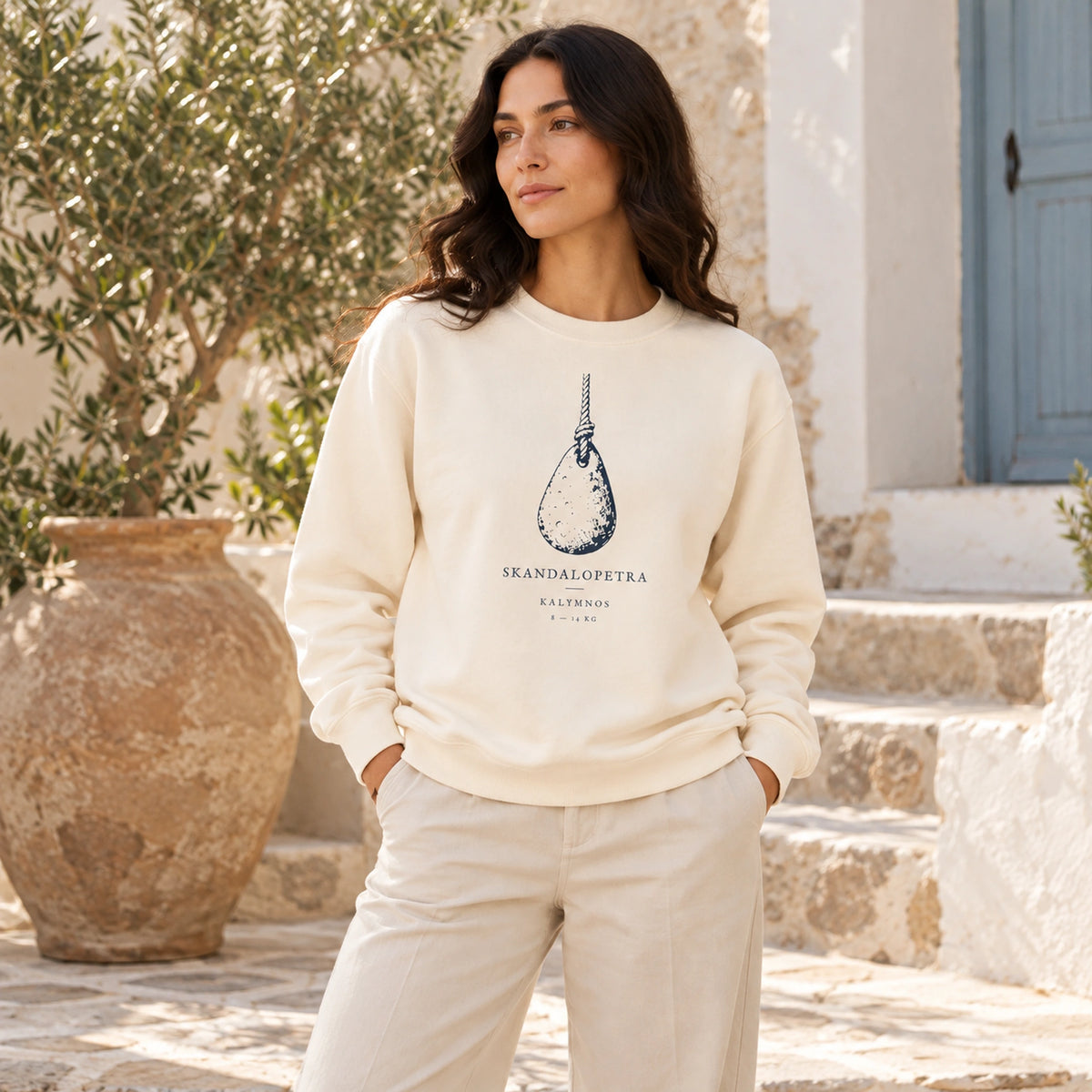 Female model wearing Skandalopetra Ivory lightweight crewneck in a Mediterranean courtyard, front view
