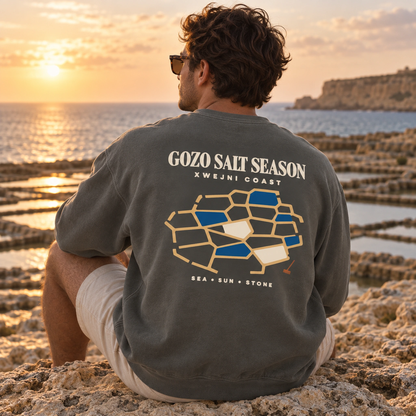 Lifestyle view of the Gozo Salt Season Comfort Colors 1566 sweatshirt in Pepper with the Xwejni Coast design shown accurately.