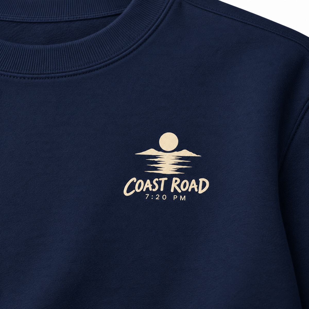Close-up of the Coast Road 7:20 PM cream left-chest print on True Navy sweatshirt fabric.