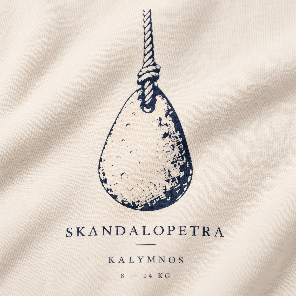 Close macro view of Skandalopetra Kalymnos diving-stone navy front design on Ivory crewneck