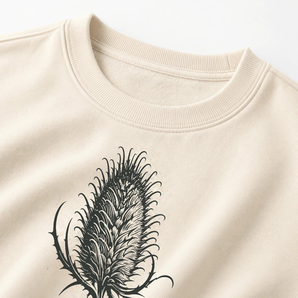 Close crop of Cardó Ivory crewneck neckline and original charcoal teasel front print