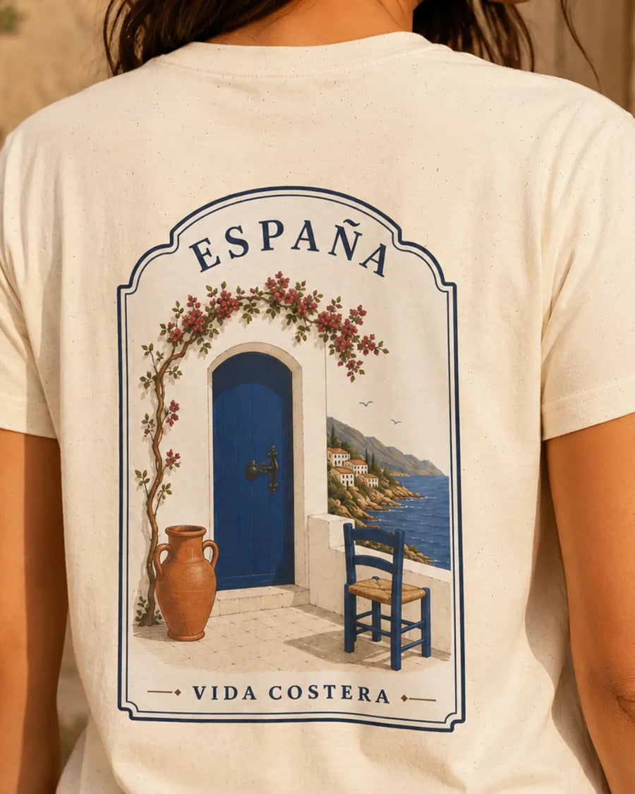 Model wearing the Natural España Vida Costera T-shirt with the large Spanish Mediterranean coastal illustration visible on the back.