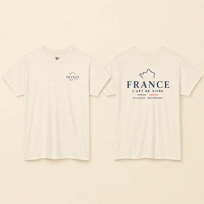 Two views of an off-white short-sleeve t-shirt on a light beige background. The front view shows a small navy blue graphic on the left chest with the word 'FRANCE' and a mountain outline.