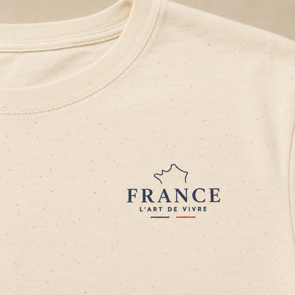 Close-up of a cream-colored textured t-shirt featuring a navy blue graphic of the map of France with the text 'FRANCE L'ART DE VIVRE' and a small red accent line.
