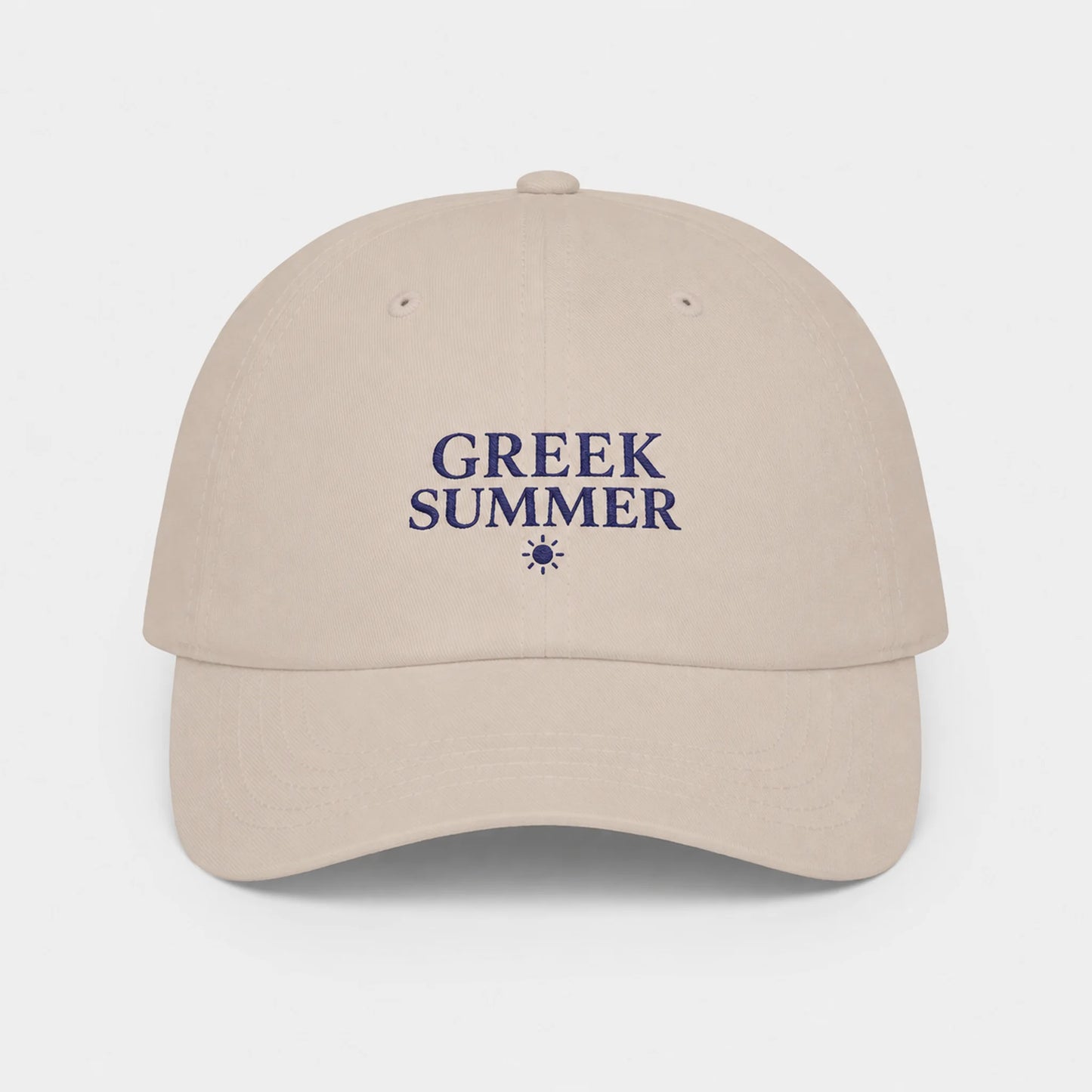 A stone baseball cap with 'GREEK SUMMER' embroidered in navy blue on the front, accompanied by a small sun icon, set against a light gray background.