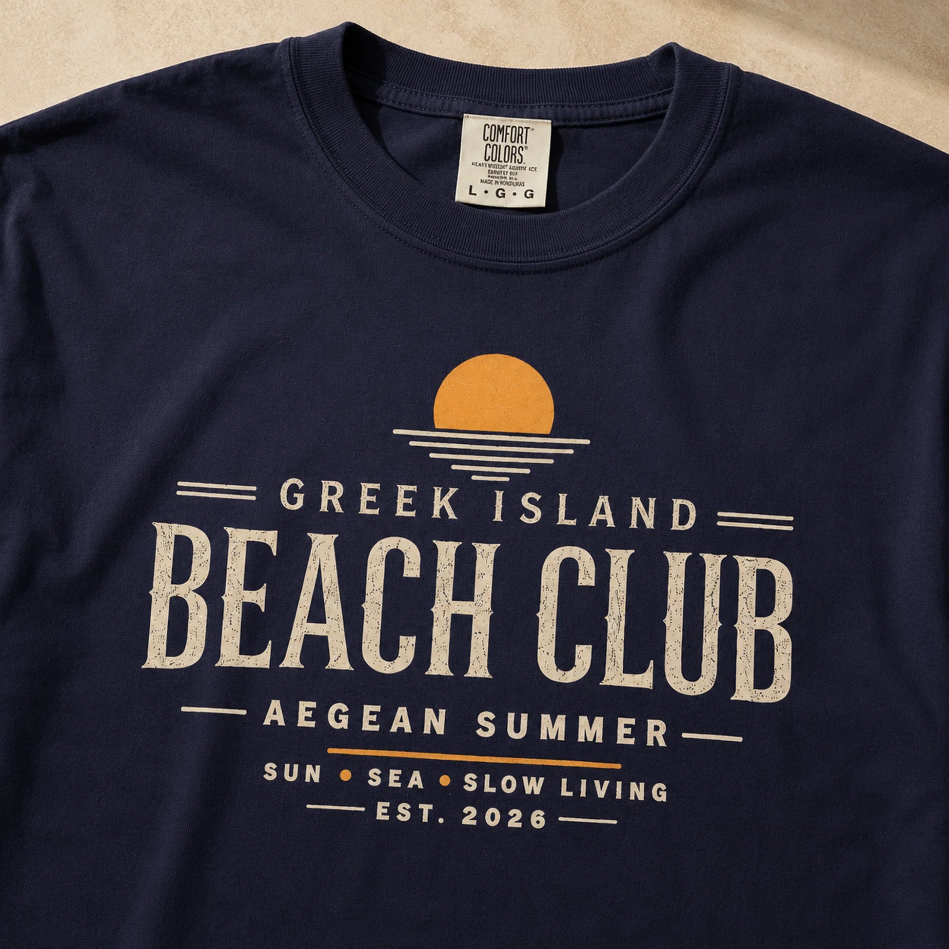 Navy blue t-shirt with 'Greek Island Beach Club' graphic design on a beige background