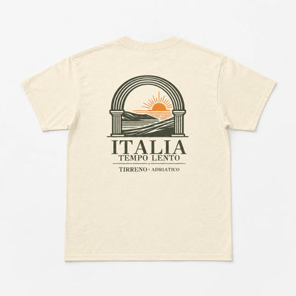 A cream-colored short-sleeve t-shirt with a graphic print on the back. The graphic features a dark olive green archway with a yellow-orange rising sun over hills, above the text 'ITALIA TEMPO LENTO' and 'TIRRENO - ADRIatico'.