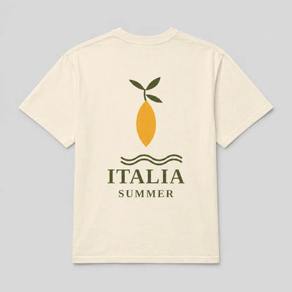 A cream-colored short-sleeve t-shirt with a graphic on the front depicting a yellow lemon with green leaves, wavy lines, and the text 'ITALIA SUMMER' in dark green, set against a solid light gray background.