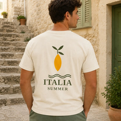 TP HERO; A man wearing a cream-colored t-shirt with a yellow lemon graphic and the text 'ITALIA SUMMER' printed on the back, standing in front of a rustic stone building.