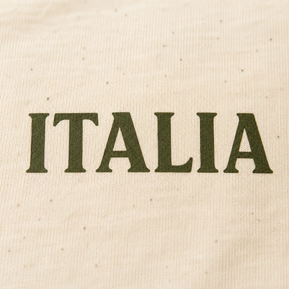 Close-up of a cream-colored woven fabric with the word 'ITALIA' printed across the center in dark olive green serif letters.