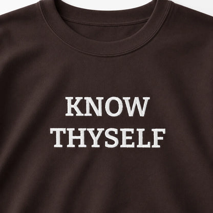 Close-up of the Dark Chocolate Know Thyself crewneck sweatshirt with the white embroidered KNOW THYSELF chest design.