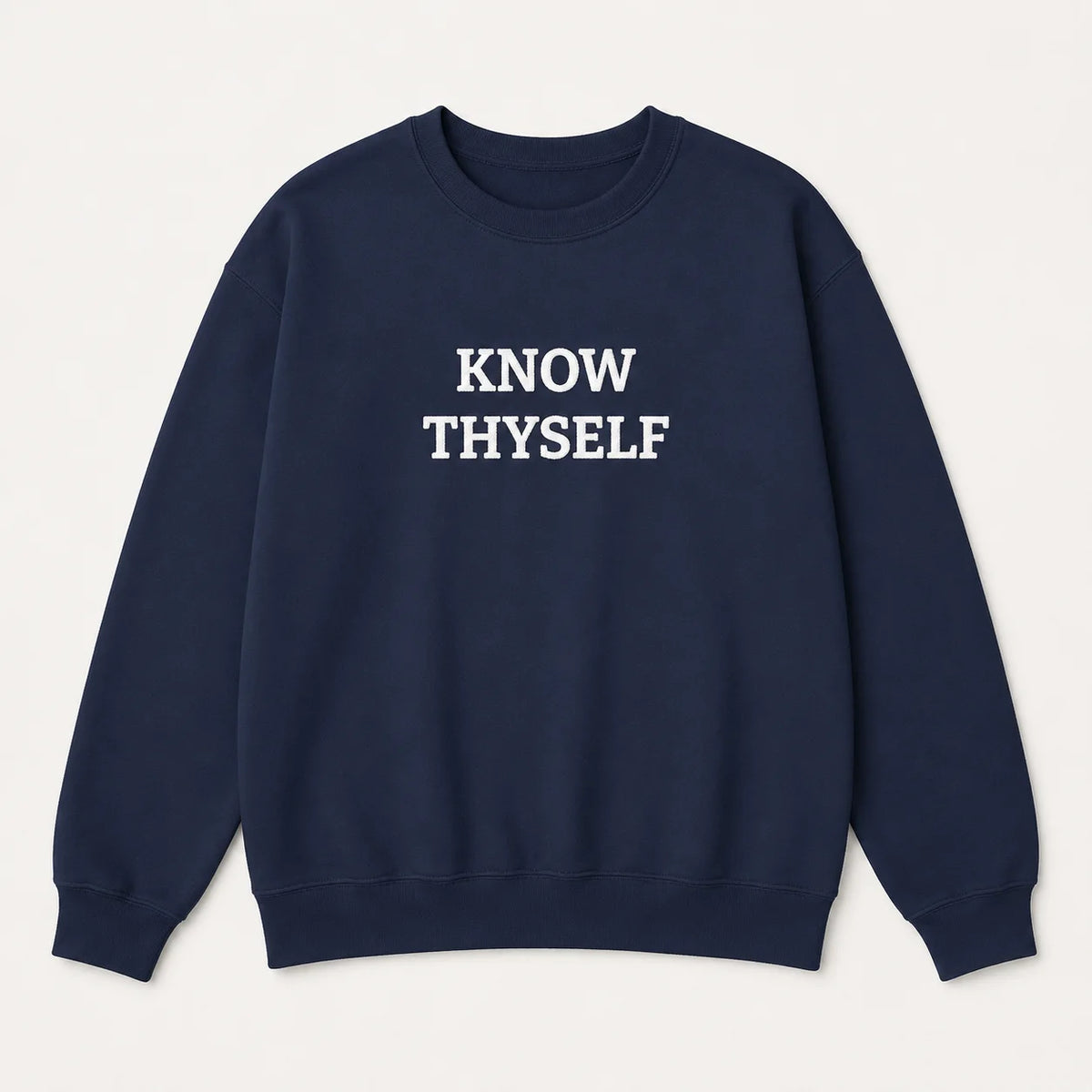 A navy blue crewneck sweatshirt with the words 'KNOW THYSELF' embroidered in white block letters across the chest, displayed flat against a light cream background.