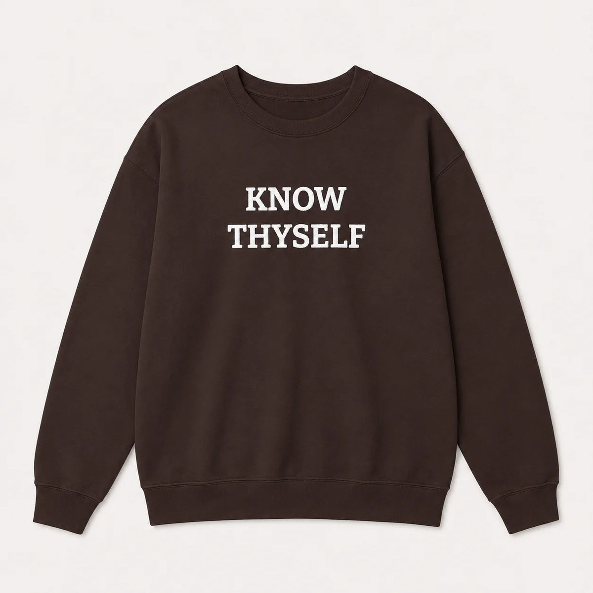 A dark brown crewneck sweatshirt with the text 'KNOW THYSELF' embroidered in white capital letters across the chest, displayed flat against a light off-white background.