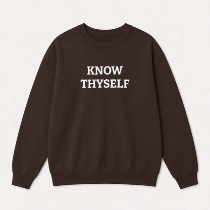 A dark brown crewneck sweatshirt with the text 'KNOW THYSELF' embroidered in white capital letters across the chest, displayed flat against a light off-white background.