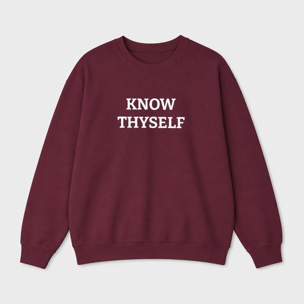 A crewneck sweatshirt in maroon with the words 'KNOW THYSELF' embroidered in white block letters across the chest, displayed on a clean light gray background.