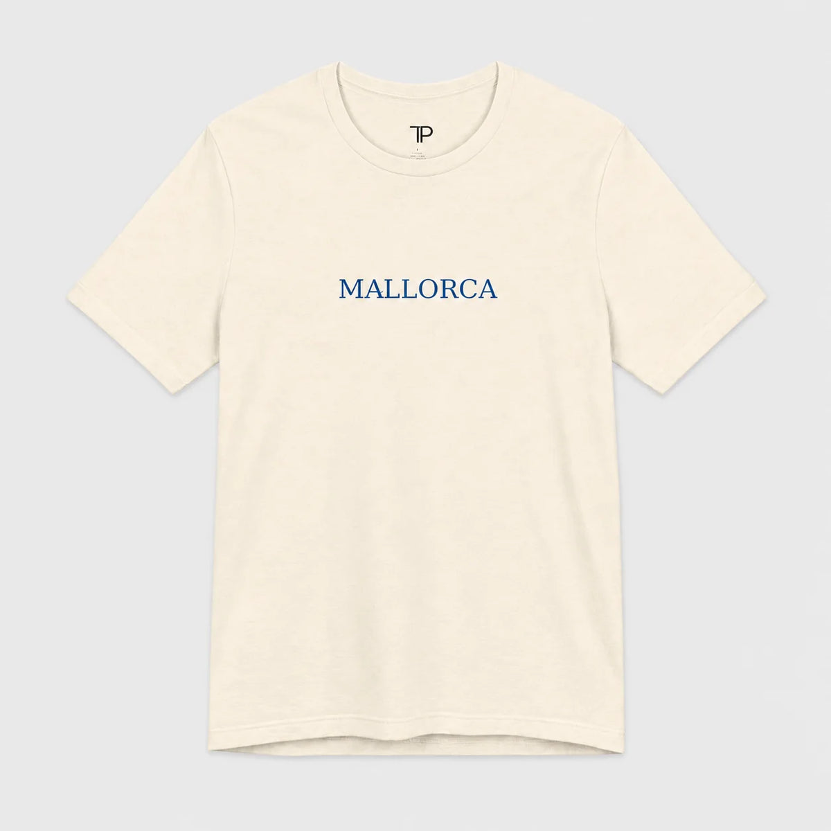 An off-white crewneck t-shirt with 'MALLORCA' printed in blue serif letters across the chest, displayed on a light gray background.