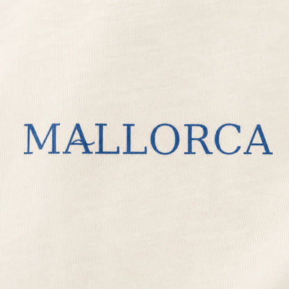Close-up of a cream-colored fabric surface with the word 'MALLORCA' printed in blue serif letters across the center.