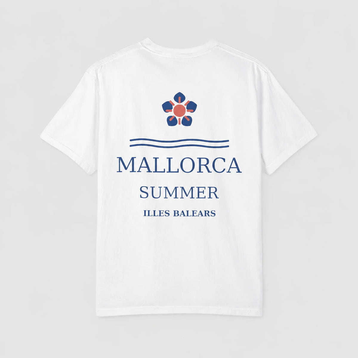 A white short-sleeve t-shirt with a blue and red graphic print on the front. The design features a flower-like emblem above the text 'MALLORCA SUMMER ILLES BALEARS' in blue, set against a light gray background.