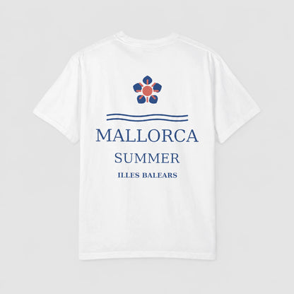 A white short-sleeve t-shirt with a blue and red graphic print on the front. The design features a flower-like emblem above the text 'MALLORCA SUMMER ILLES BALEARS' in blue, set against a light gray background.