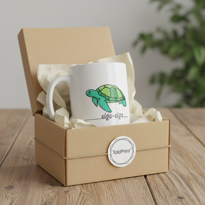 White mug with a green turtle design in a brown gift box on a wooden surface.