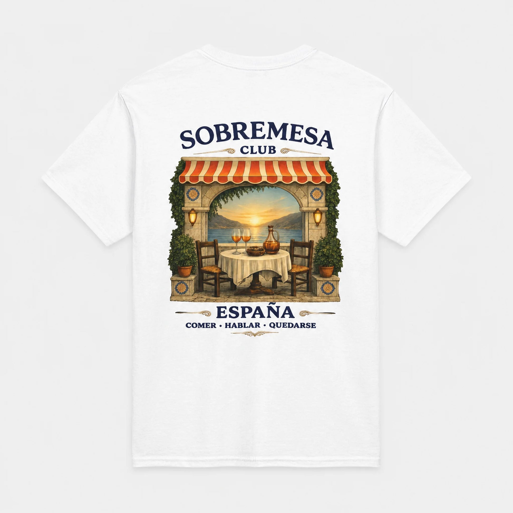 A white short-sleeve t-shirt with a graphic print on the front depicting a Spanish outdoor restaurant scene under a red and white striped awning, with the text 'SOBREMESA CLUB' and 'ESPAÑA COMER - HABLAR - QUEDARSE'.