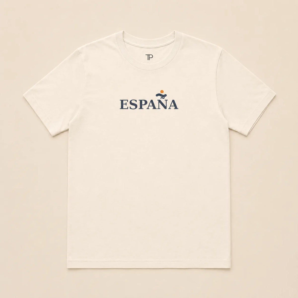 An off-white short-sleeve crewneck t-shirt with 'ESPAÑA' printed in navy blue across the chest, featuring a small yellow and blue graphic above the text, laid flat on a light beige background.