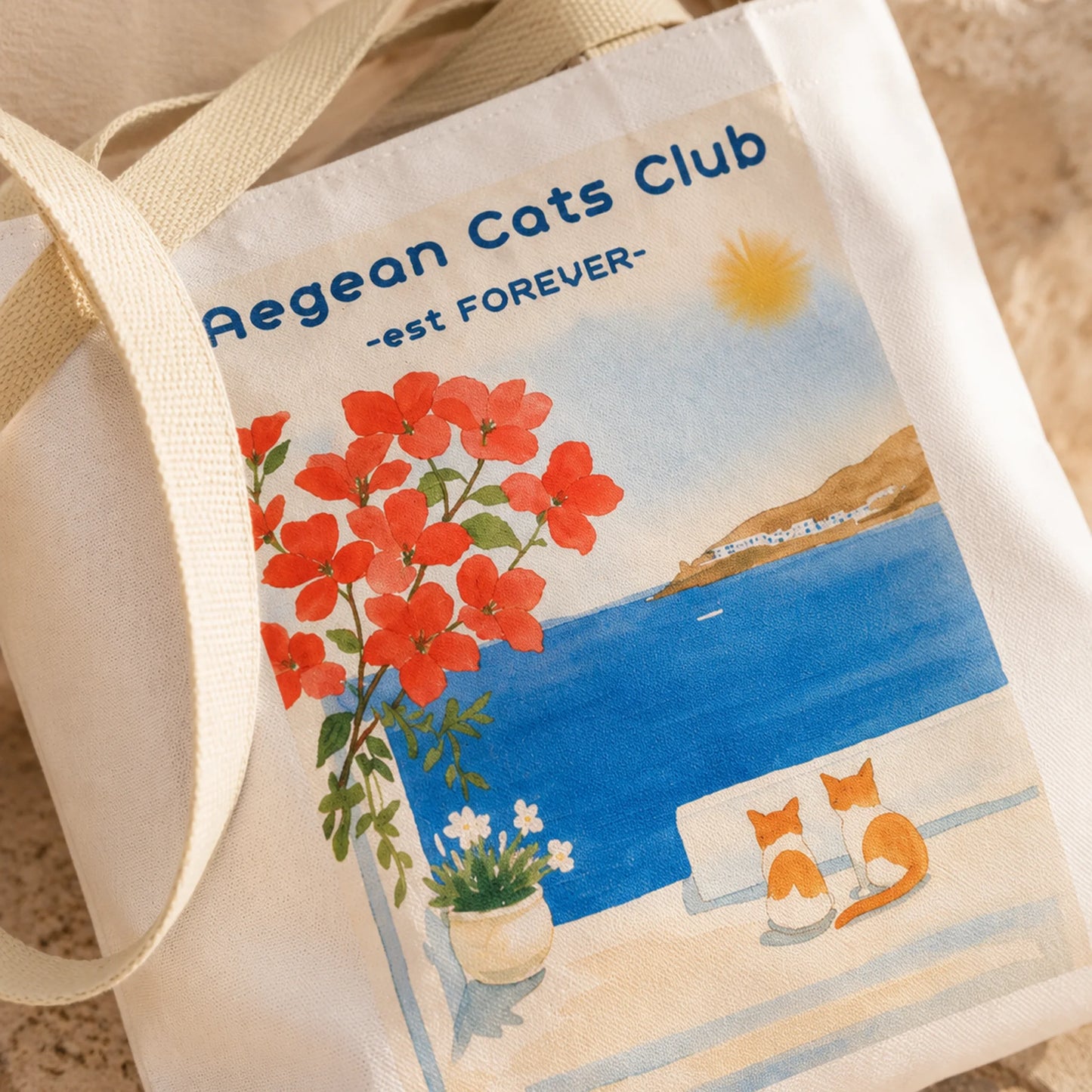 Tote bag with Aegean Cats Club design featuring a cat, flowers, and ocean.