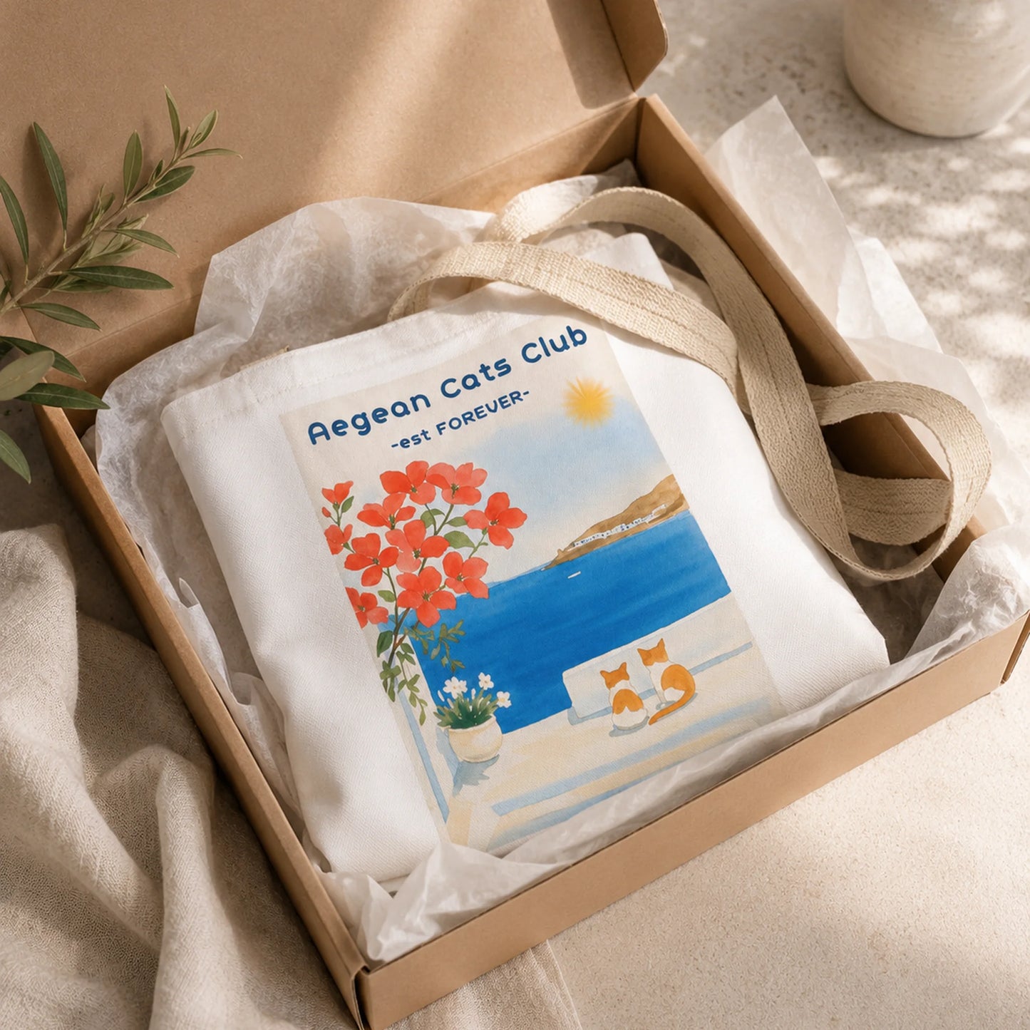 White tote bag with 'Aegean Cats Club' design in a brown box