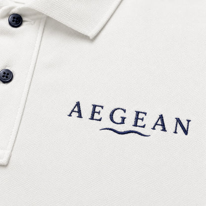 Close-up of a white polo shirt with the brand name 'AEGEAN' embroidered in navy blue on the chest, featuring a two-button placket.