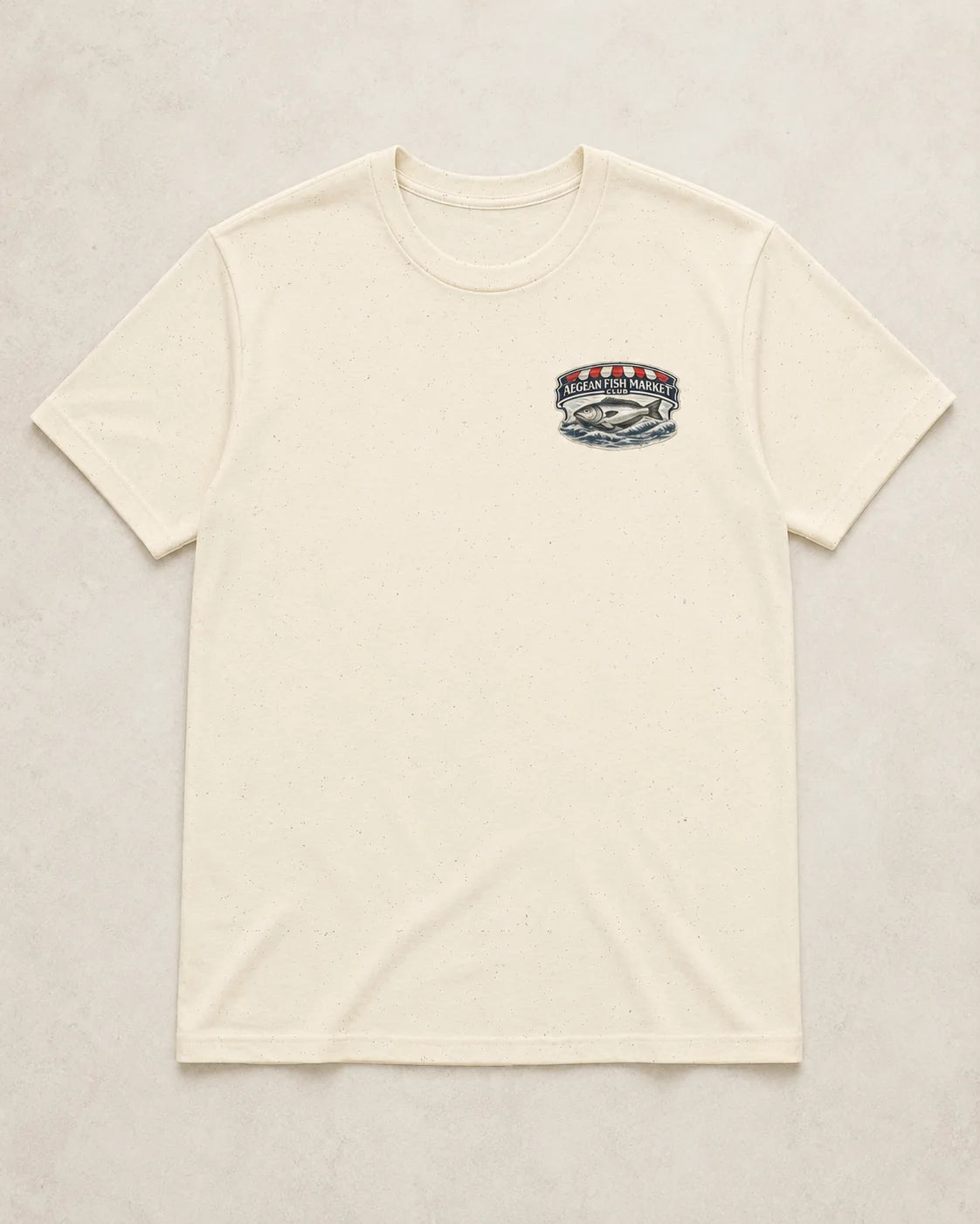 An off-white crewneck t-shirt with a small multicolor graphic on the left chest, laid flat against a light beige textured background.