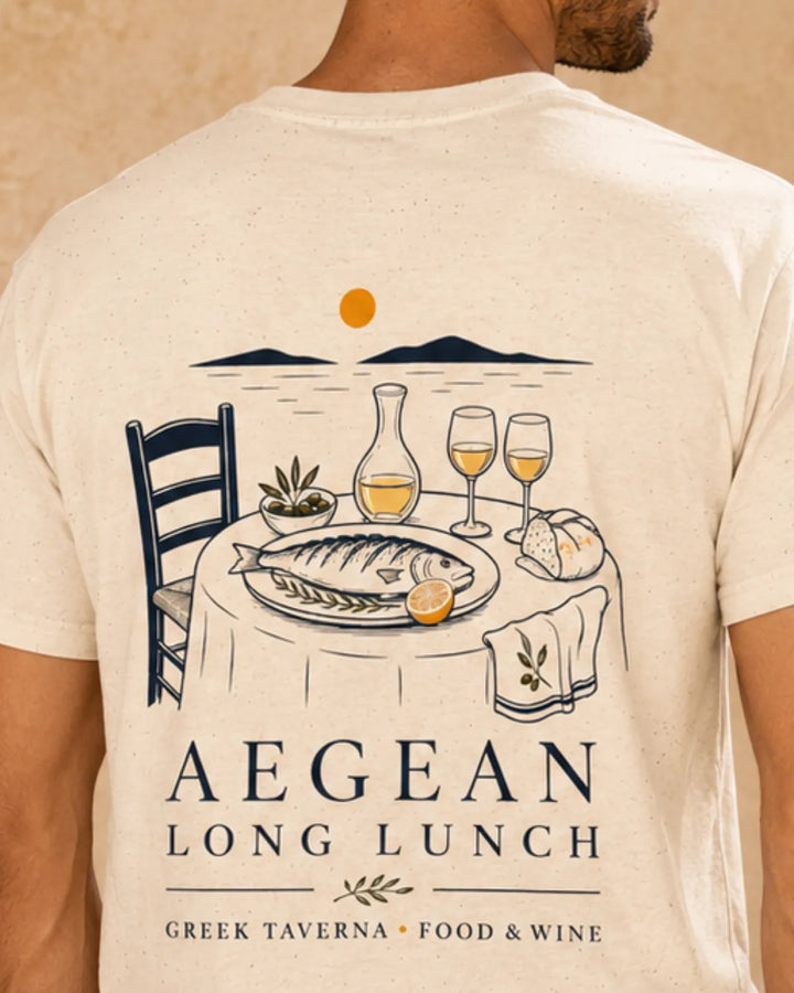 Model wearing a natural t-shirt with a detailed graphic print of a Greek taverna lunch scene and the text 'AEGEAN LONG LUNCH' on the back