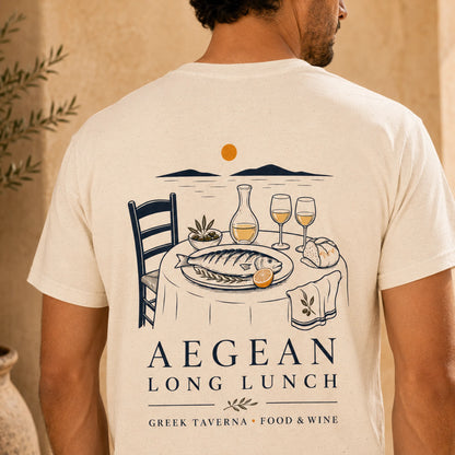 TP HERO: A man viewed from behind wearing a natural t-shirt with a detailed graphic print of a Greek taverna lunch scene and the text 'AEGEAN LONG LUNCH' on the back.
