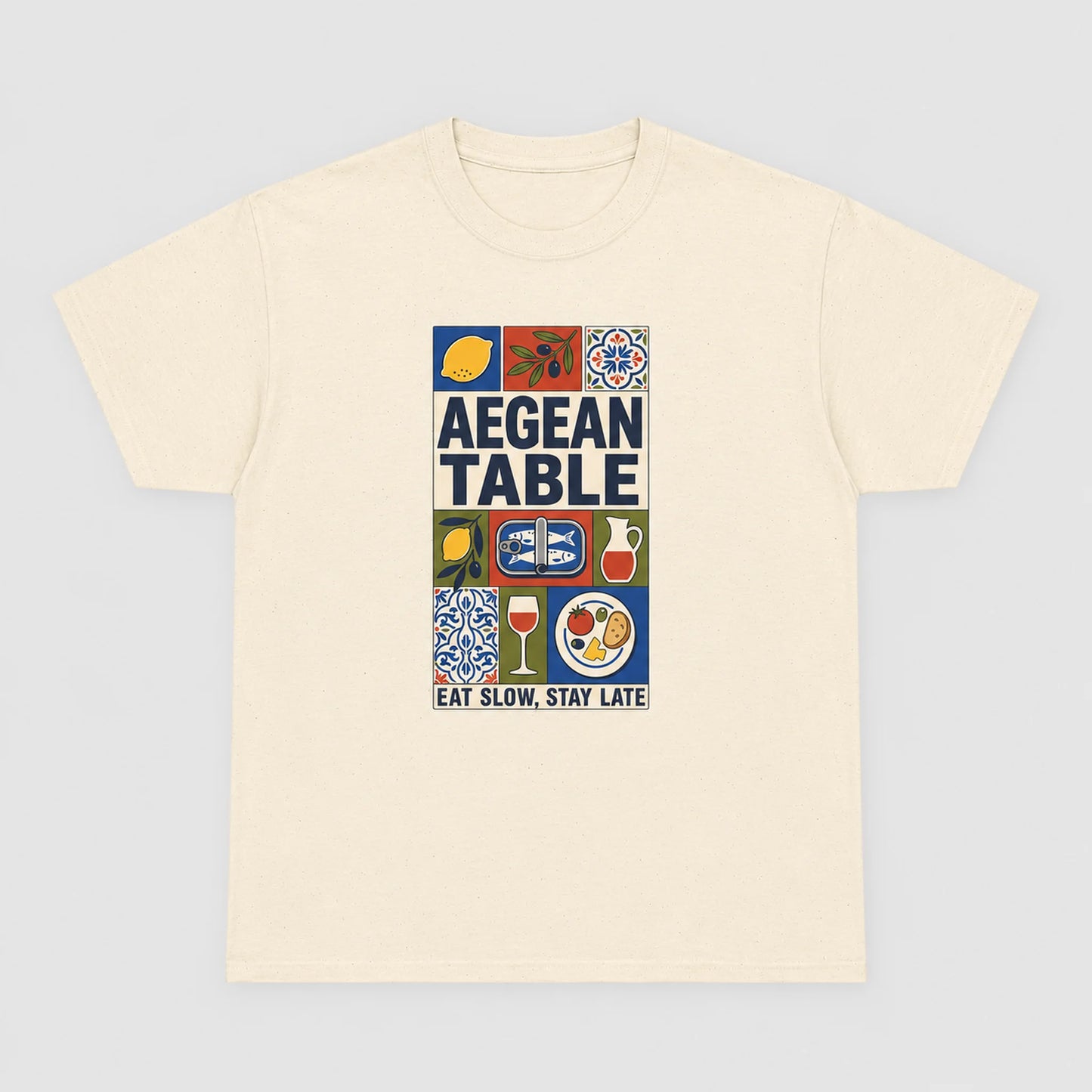 Beige t-shirt with 'Aegean Table' graphic design on a light gray background