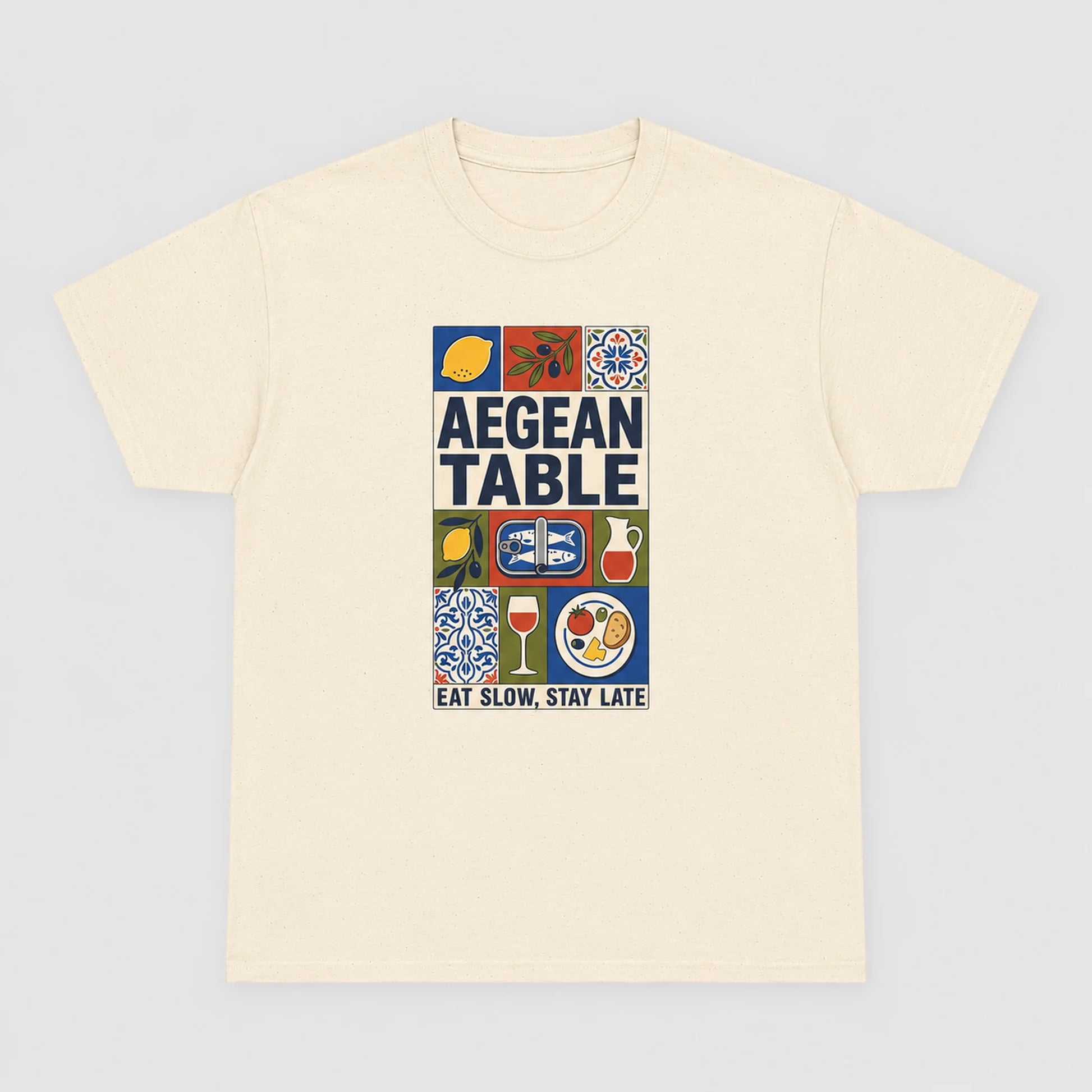 Beige t-shirt with 'Aegean Table' graphic design on a light gray background