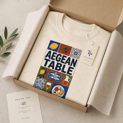 White sweatshirt with 'Aegean Table' design in a box, featuring Tolpint branding.
