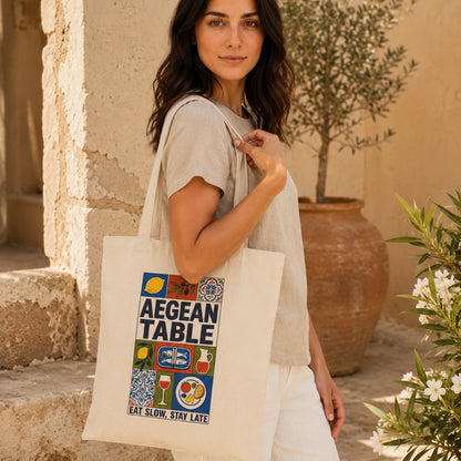 Woman holding a tote bag with 'Aegean Table' design outdoors.