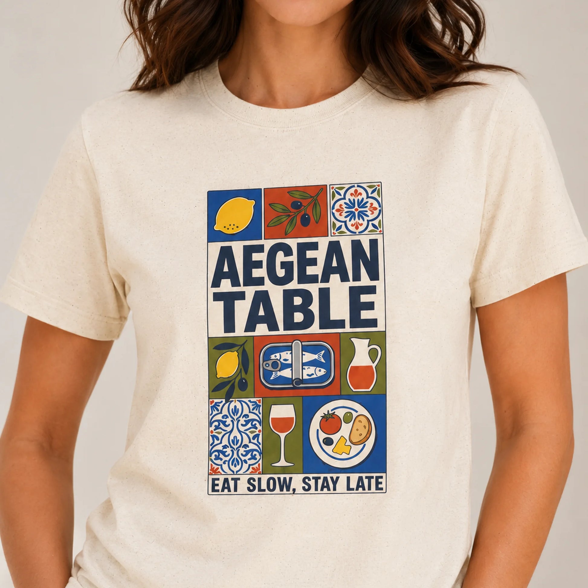 TP HERO: Person wearing a t-shirt with 'Aegean Table' design featuring food and drink icons.