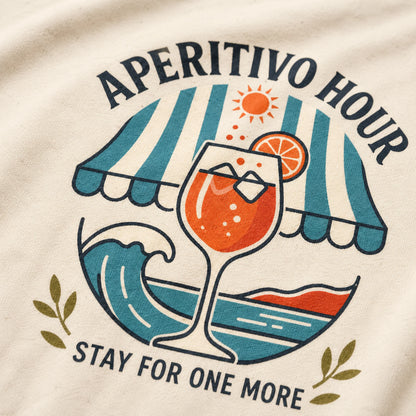 T-shirt design with a cocktail graphic and 'Aperitivo Hour, Stay for One More' text on a beige background.